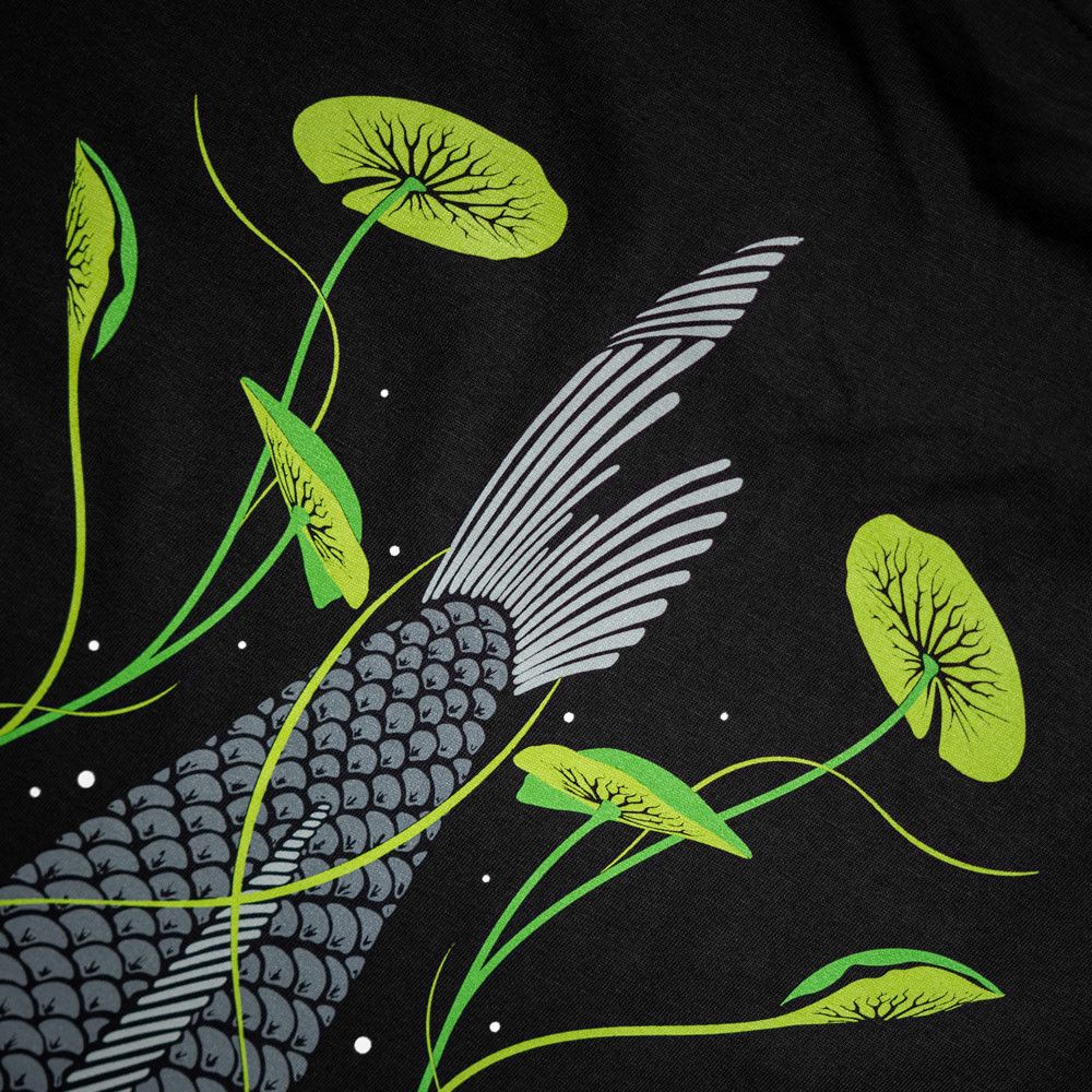 Kumu Camiseta Tails Up Está inspirado en uno de los momentos más fascinantes : una carpa alimentándose entre lirios, rodeada de burbujas.